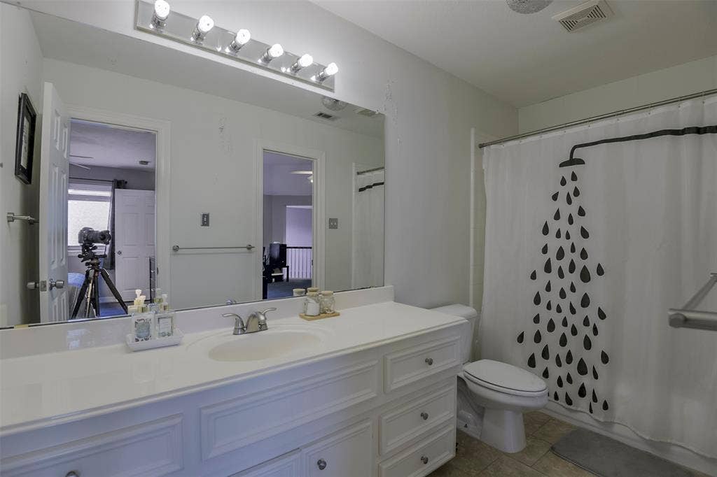 1200 Lakeway Drive, Plano, TX 75075 Bathroom with an integrated vanity sink, white cabinetry, a large wall-mounted mirror, and a shower-tub combination