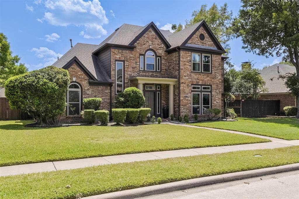 1200 Lakeway Drive, Plano, TX 75075 Brick and siding exterior with arched and rectangular windows, covered entry, and manicured landscaping