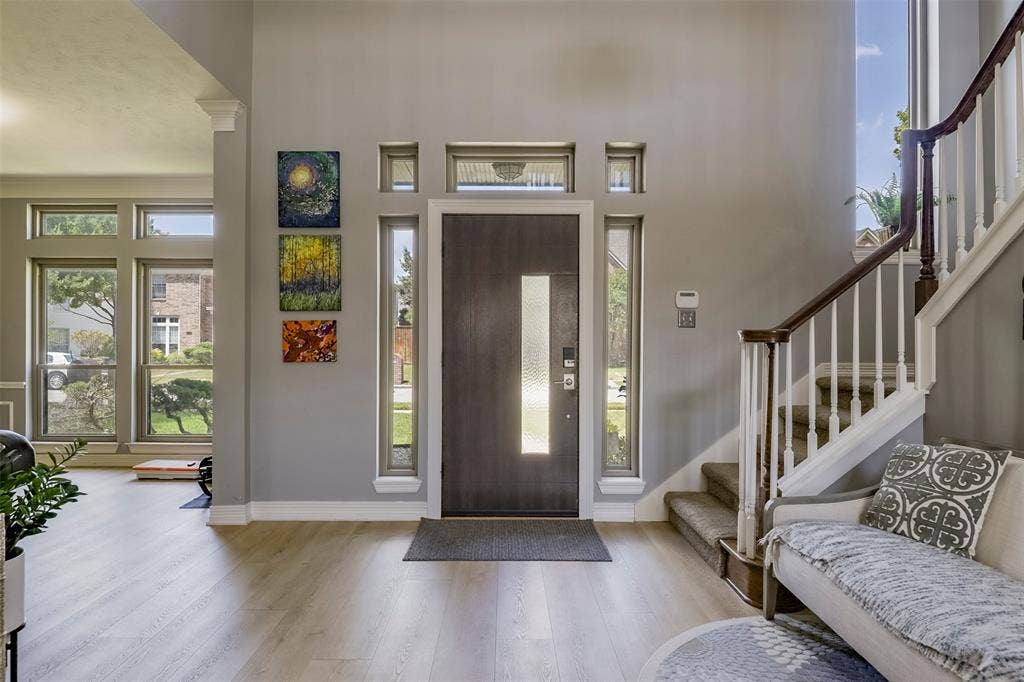 1200 Lakeway Drive, Plano, TX 75075 Two-story entryway featuring a dark wood-finish door with frosted glass insert, flanked by tall vertical windows and transom windows