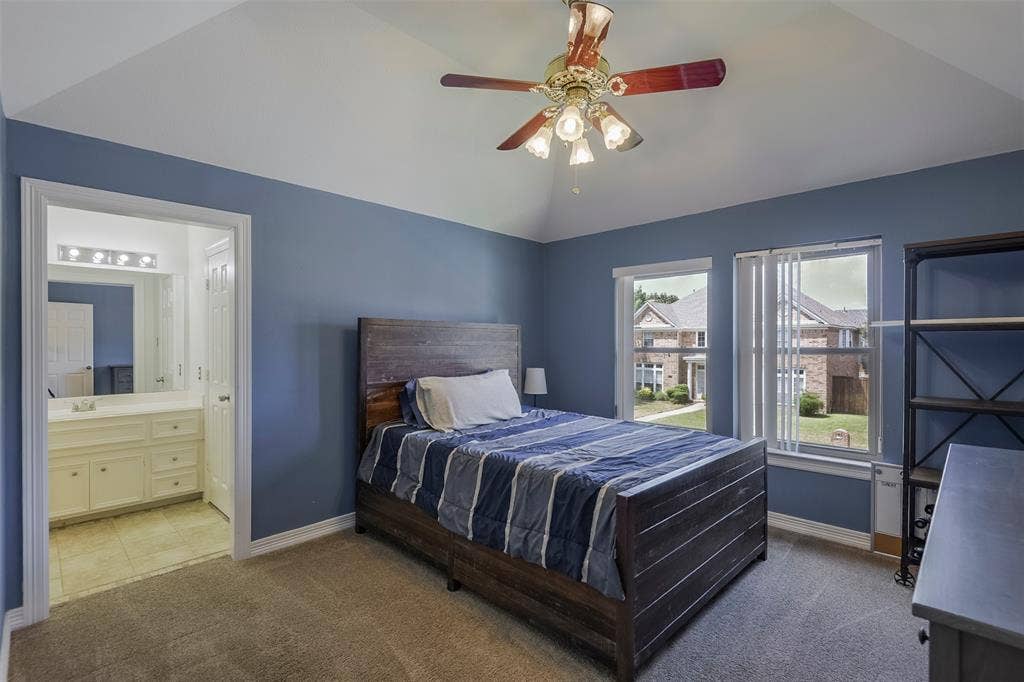 1200 Lakeway Drive, Plano, TX 75075 Vaulted ceiling with a ceiling fan, dual windows, and an en-suite bathroom featuring a vanity with a rectangular mirror and sconce lighting
