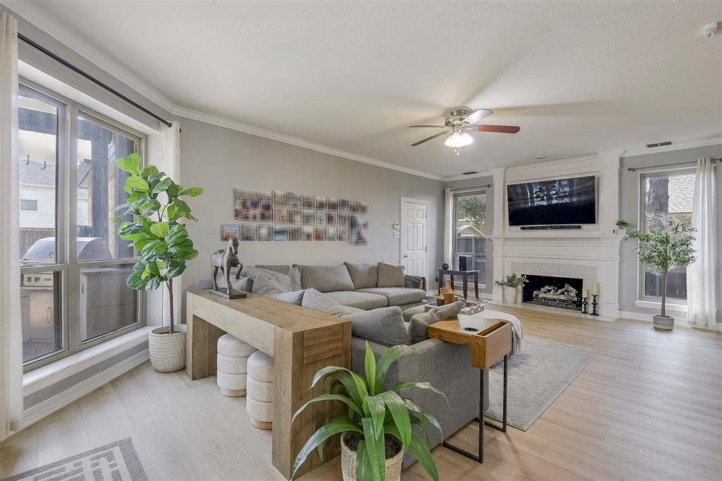 1200 Lakeway Drive, Plano, TX 75075 Living area featuring wood-finish flooring, a ceiling fan, and a fireplace with a stone mantel