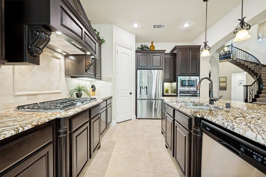 This Chef’s gourmet kitchen features upgraded cabinetry, light-toned granite countertops, high-end stainless steel appliances, and integrated, pull-out spice racks for optimal storage.
