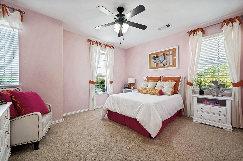 This upstairs secondary bedroom features a ceiling fan, a walk-in closet, abundant natural light from multiple windows, and direct access to a Jack and Jill bathroom.