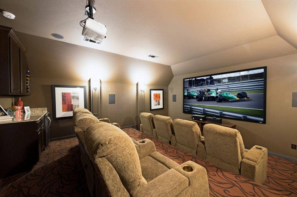 Fabulous Bi-level 8-Seat Home Theater featuring a ceiling-mounted projector, screen, built-in cabinetry with granite countertops and wine refrigerator.