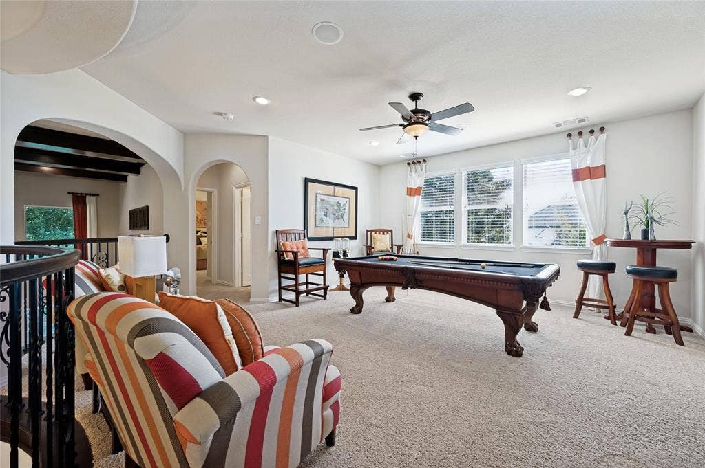 This exceptional game room is ideal for entertaining, featuring abundant natural light, a dedicated sitting area, recessed lighting, a ceiling fan, and is adjacent to the home theater.