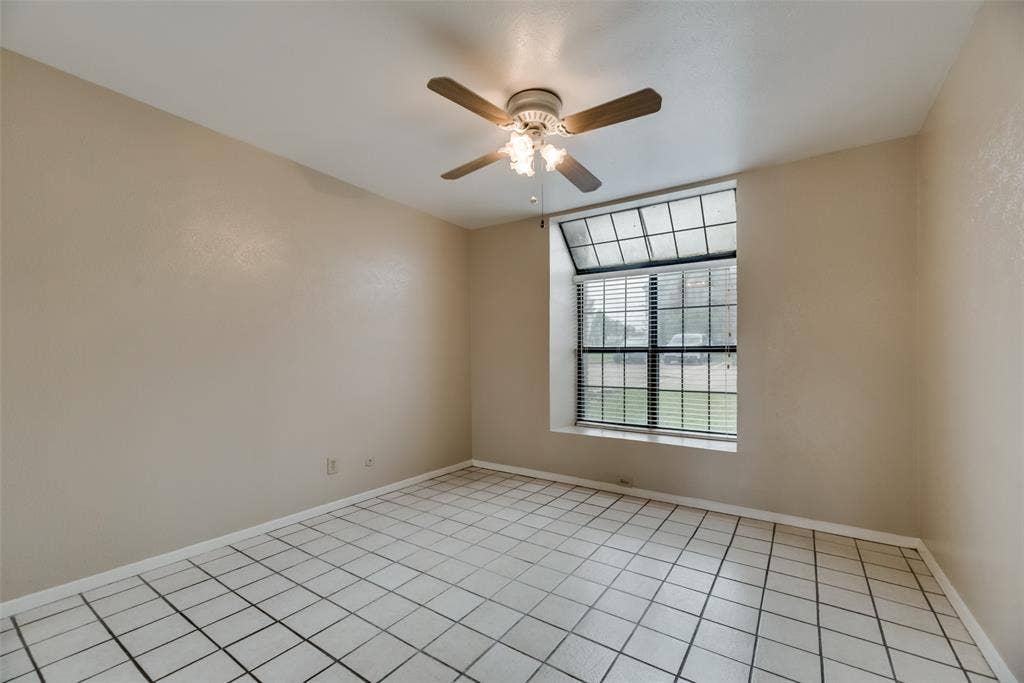 Tiled empty room featuring ceiling fan
