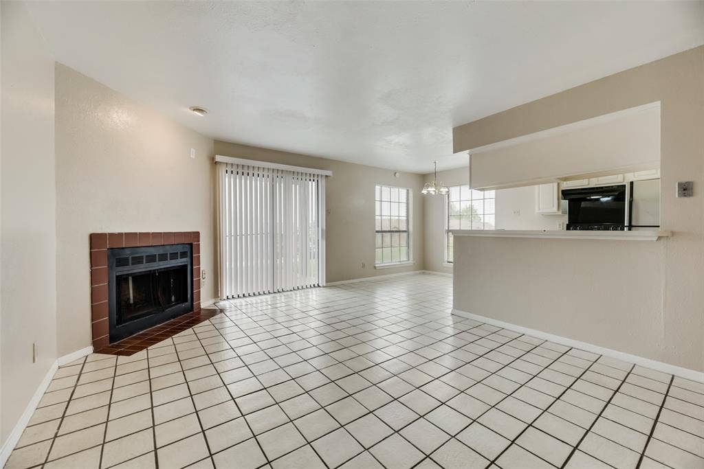 Unfurnished living room featuring an inviting chandelier, light tile floors, and a fireplace