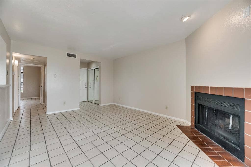Unfurnished living room with a fireplace and light tile flooring