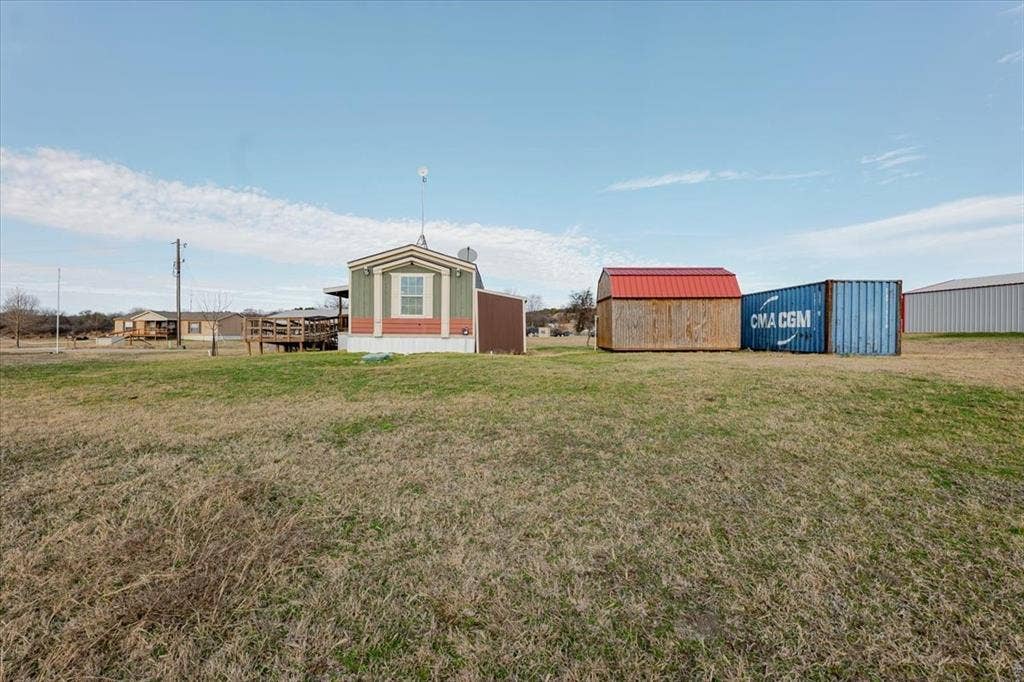 126 Starry Sky Court, Springtown, TX 76082 Manufactured home with gray siding and white trim, featuring a raised wooden deck and storage units.