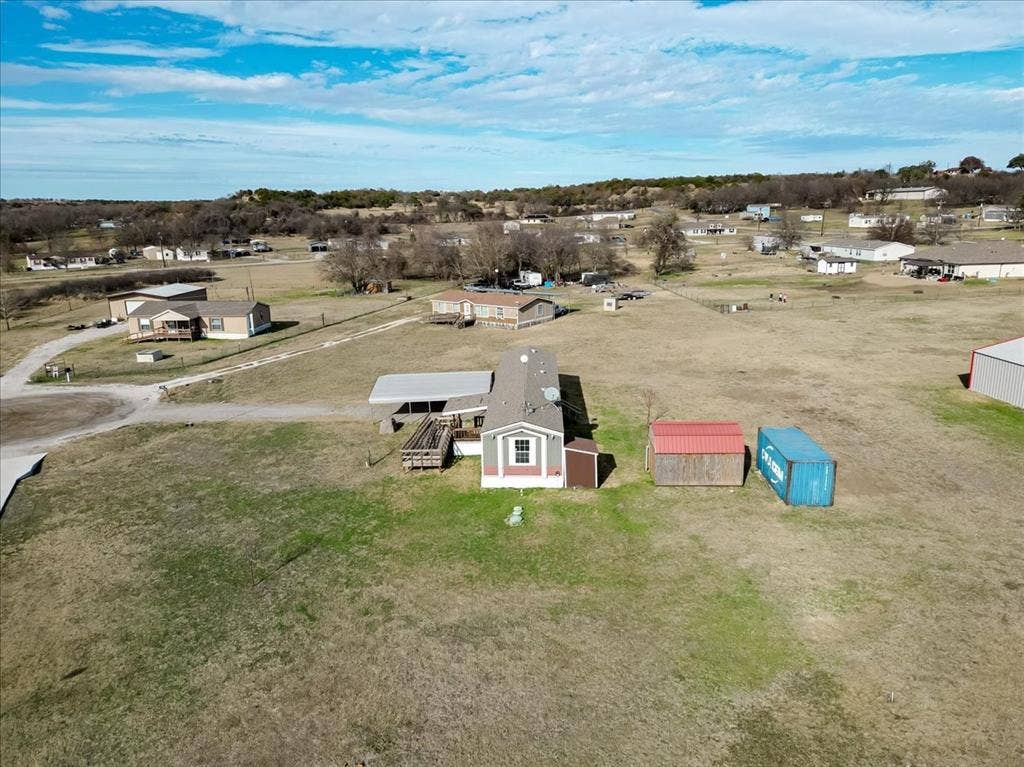 126 Starry Sky Court, Springtown, TX 76082 Expansive lot featuring a single-story residence with covered parking and additional storage structures