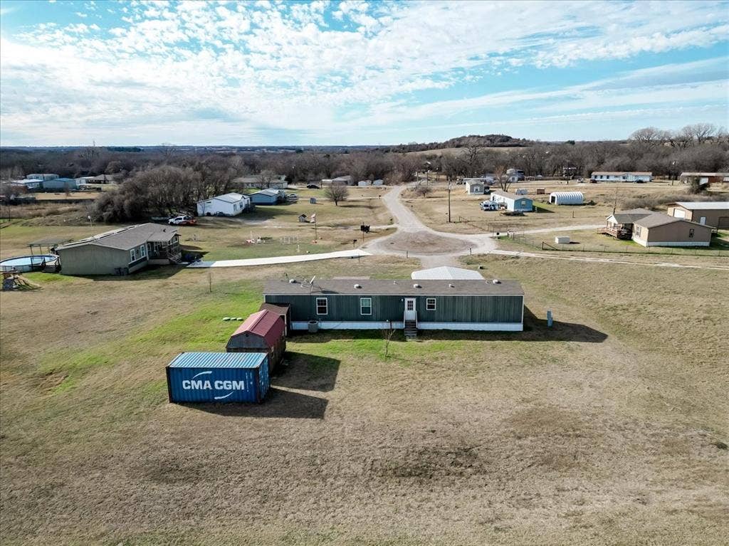 126 Starry Sky Court, Springtown, TX 76082 Rear view of mobile home and storage units.