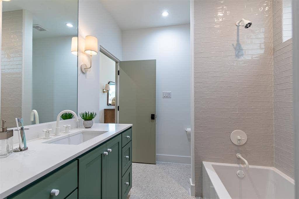 6979 Bob O Link Drive, Dallas, TX 75214 Bathroom featuring a deep green vanity with white knobs, a white countertop with an integrated sink, and white fixtures