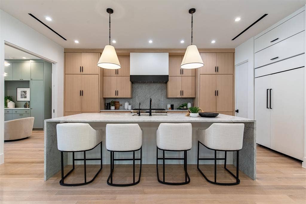 6979 Bob O Link Drive, Dallas, TX 75214 Modern kitchen featuring a large waterfall island with seating, light wood-finish cabinetry, integrated appliances, and recessed lighting
