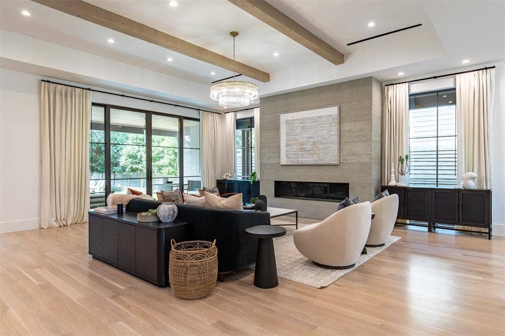 6979 Bob O Link Drive, Dallas, TX 75214 Open-concept living space featuring wood-finish flooring, a linear fireplace set into a stone-clad wall, and exposed ceiling beams