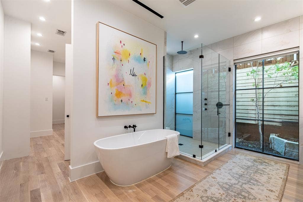 6979 Bob O Link Drive, Dallas, TX 75214 Freestanding soaking tub with matte black fixtures, a spacious glass-enclosed shower, and a large window providing natural light
