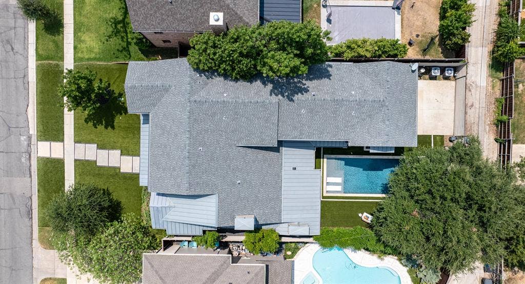 6979 Bob O Link Drive, Dallas, TX 75214 Expansive property featuring a grey shingle roof, a rectangular swimming pool with integrated tanning ledge, and a manicured lawn