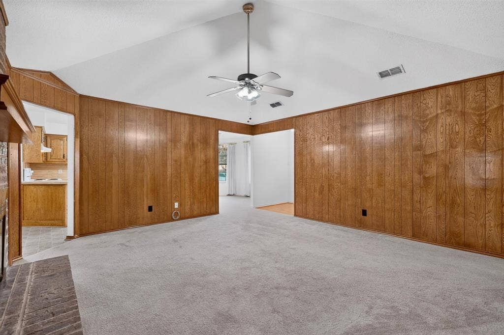 303 Stoneybrook Drive, Wylie, TX 75098 Vaulted ceiling with a ceiling fan, wood-paneled walls, and carpet flooring