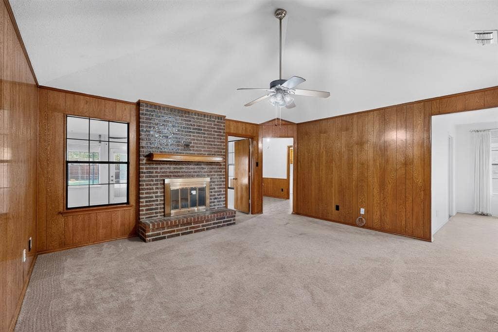 303 Stoneybrook Drive, Wylie, TX 75098 Brick fireplace with a wood-finish mantel, vaulted ceiling, ceiling fan, and wood-paneled walls