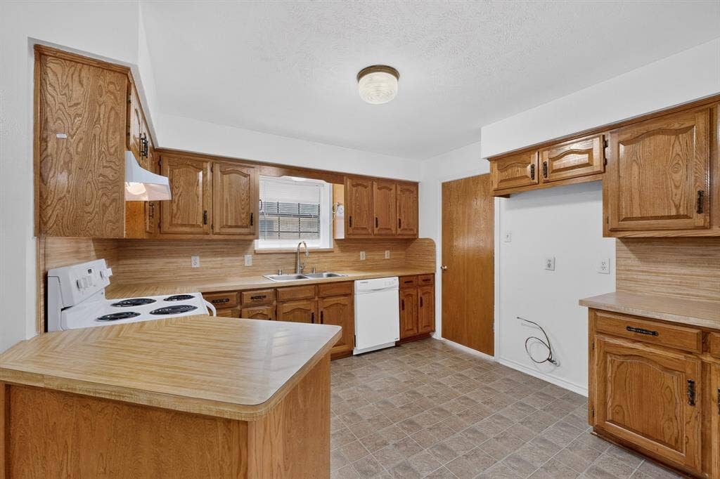 303 Stoneybrook Drive, Wylie, TX 75098 Kitchen featuring extensive wood cabinetry, a white electric range, a stainless steel sink, a white dishwasher, and durable tile flooring
