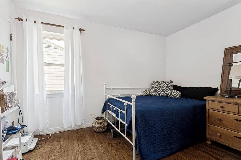 2312 Brooks Street, Garland, TX 75041 Wood-finish flooring, white painted walls, and a single window with white curtains