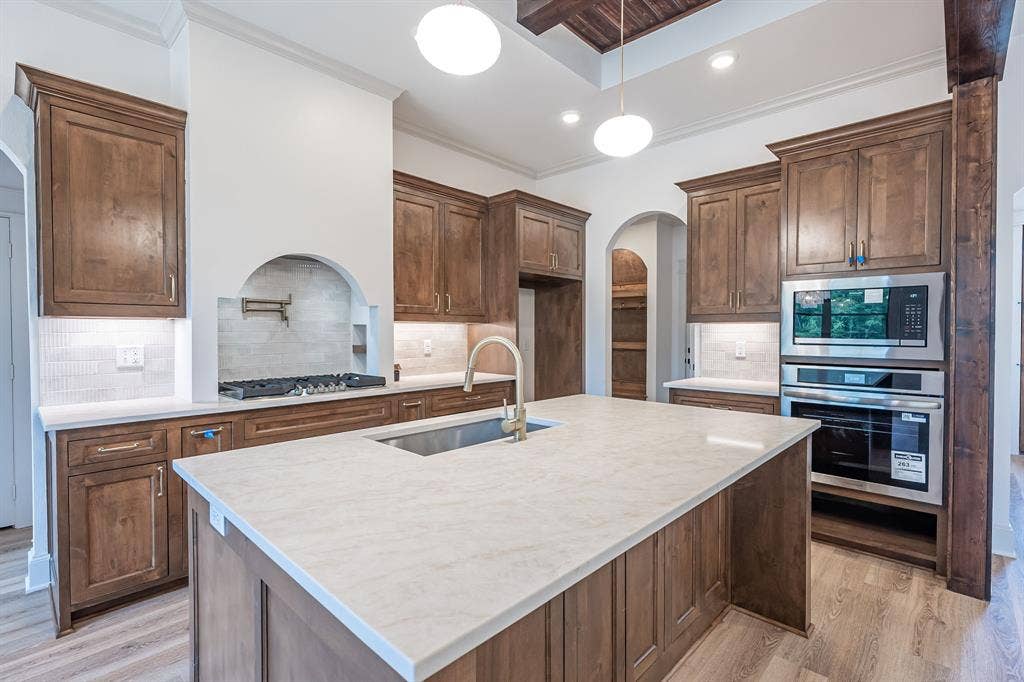 17049 Island Lake Drive, Tyler, TX 75708 Expansive kitchen island with a light-toned countertop, wood-finish cabinetry, stainless steel appliances, and a gas range