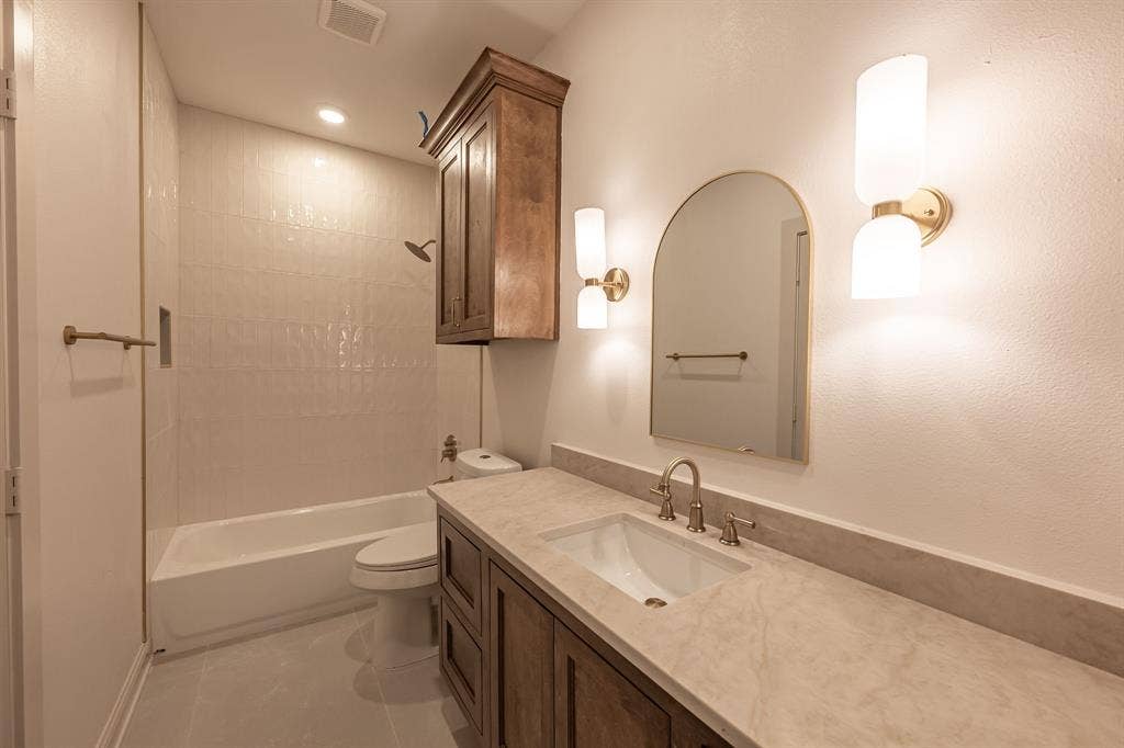 17049 Island Lake Drive, Tyler, TX 75708 Built-in vanity with a stone countertop, undermount sink, and wall-mounted sconces