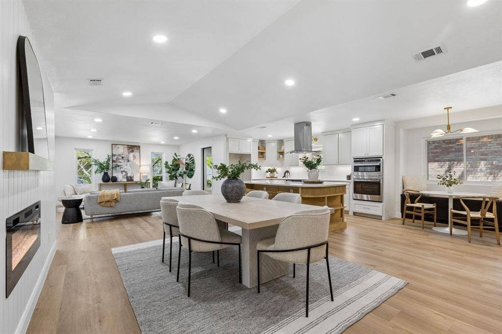 12124 Dixfield Drive, Dallas, TX 75218 Open-concept living space featuring wood-finish flooring, recessed lighting, a built-in fireplace, and a kitchen island with built-in shelving