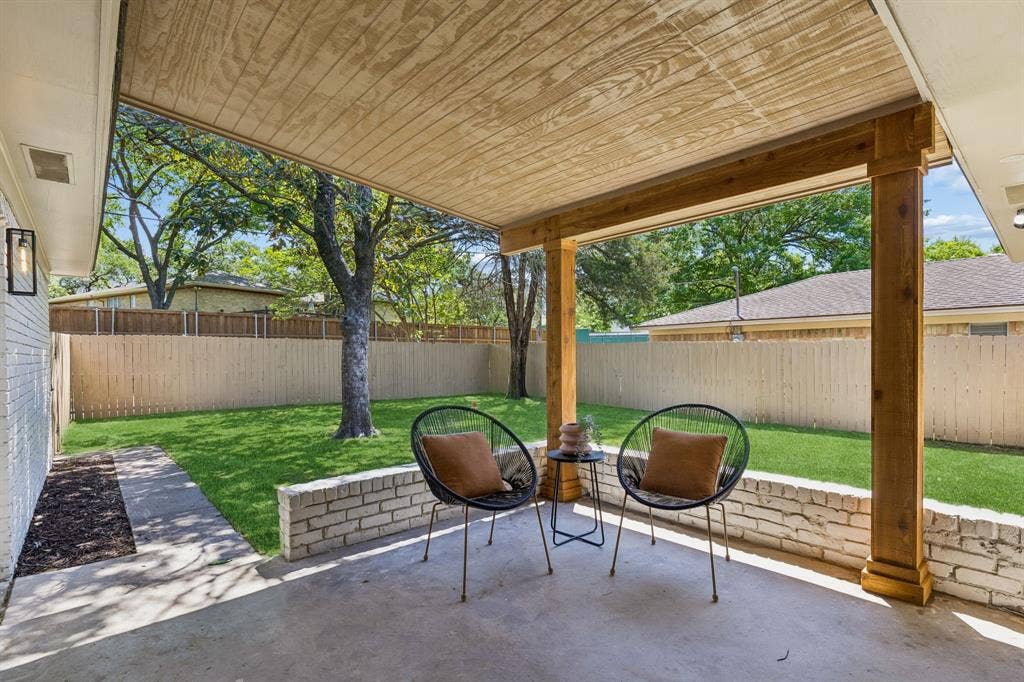 12124 Dixfield Drive, Dallas, TX 75218 Covered concrete patio with wood-finish ceiling, exposed wood beams, and a white brick half-wall