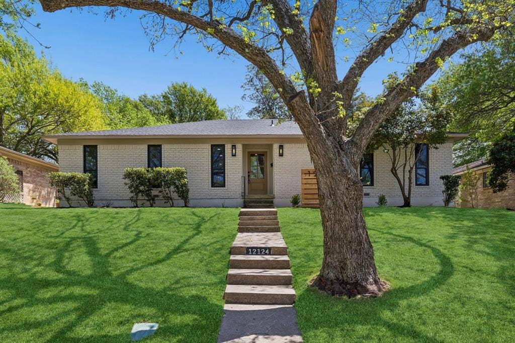 12124 Dixfield Drive, Dallas, TX 75218 Charming mid-century modern residence with a clean-lined cream exterior, metal-framed windows, and wood-finish entry steps