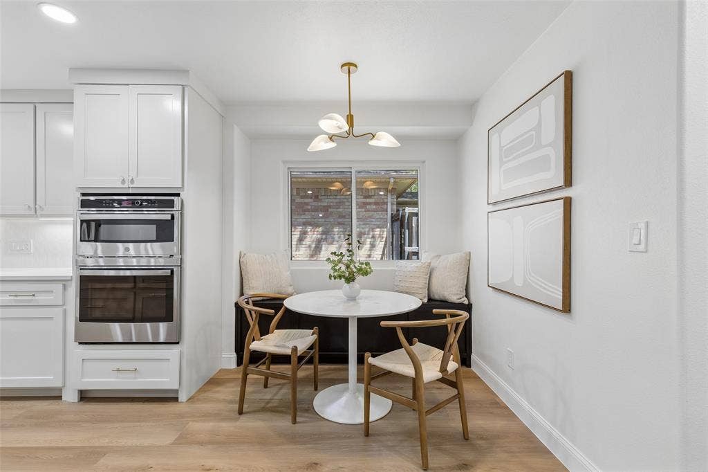 12124 Dixfield Drive, Dallas, TX 75218 Built-in banquette seating with a window, wood-finish flooring, white cabinetry, and stainless steel built-in appliances