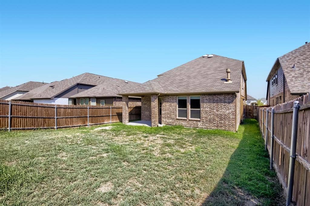 3925 Chesapeake Lane, Heartland, TX 75126 Expansive backyard featuring a privacy fence, brick exterior, and covered patio