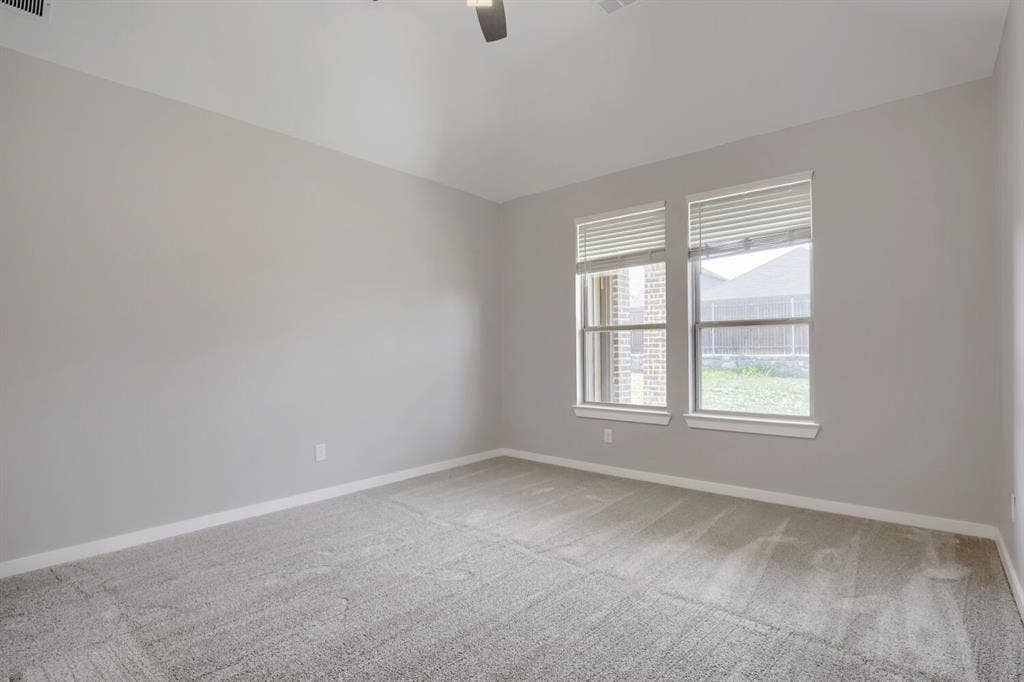 3925 Chesapeake Lane, Heartland, TX 75126 Plush carpeting, neutral wall color, two windows, and a ceiling fan with integrated lighting