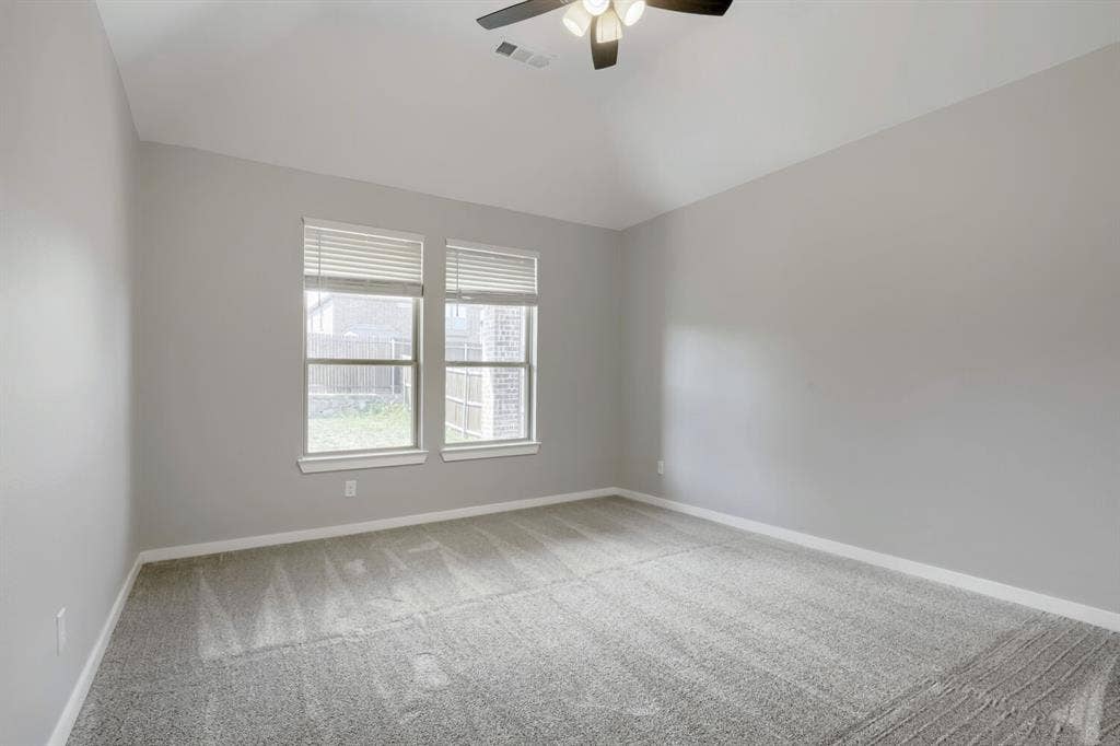 3925 Chesapeake Lane, Heartland, TX 75126 Bright secondary bedroom with expansive windows featuring plantation shutters, neutral gray walls, and plush carpeting throughout