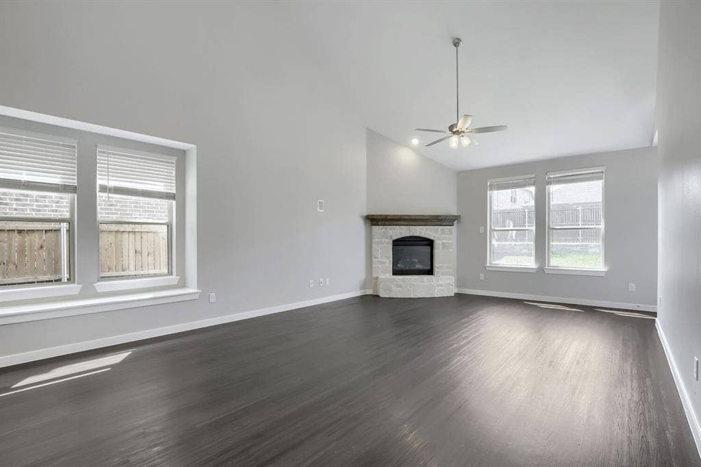 3925 Chesapeake Lane, Heartland, TX 75126 Vaulted ceiling, stone-surround fireplace with wood mantel, dark wood-finish flooring, ceiling fan, and multiple windows