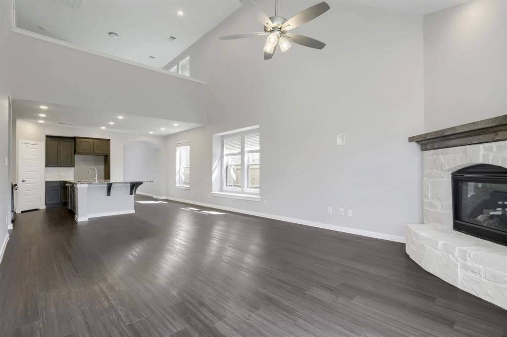 3925 Chesapeake Lane, Heartland, TX 75126 Open-concept living space featuring soaring vaulted ceilings with skylights and ceiling fan, dark wood-finish flooring throughout, and abundant natural light from multiple windows