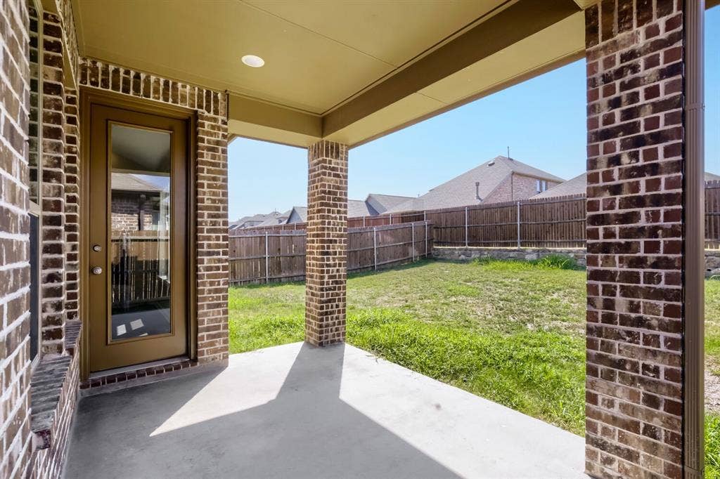 3925 Chesapeake Lane, Heartland, TX 75126 Covered patio with brick columns and ceiling detail opening to expansive fenced yard featuring mature landscaping and level lawn space