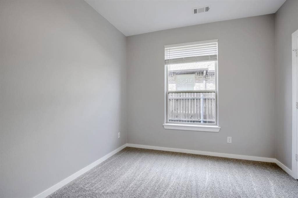 3925 Chesapeake Lane, Heartland, TX 75126 Bright secondary bedroom featuring neutral wall finishes, carpeted flooring, and a large double-hung window with horizontal blinds allowing abundant natural light