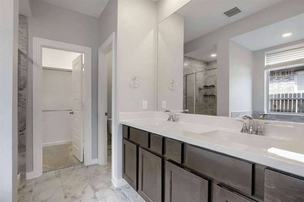 3925 Chesapeake Lane, Heartland, TX 75126 Spa-inspired primary bathroom featuring dual vanities with a quartz countertop, dark cabinetry with ample storage, and polished chrome fixtures