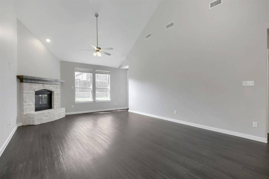 3925 Chesapeake Lane, Heartland, TX 75126 Vaulted ceilings with recessed lighting, stone-clad fireplace, dark wood-finish flooring, and a ceiling fan