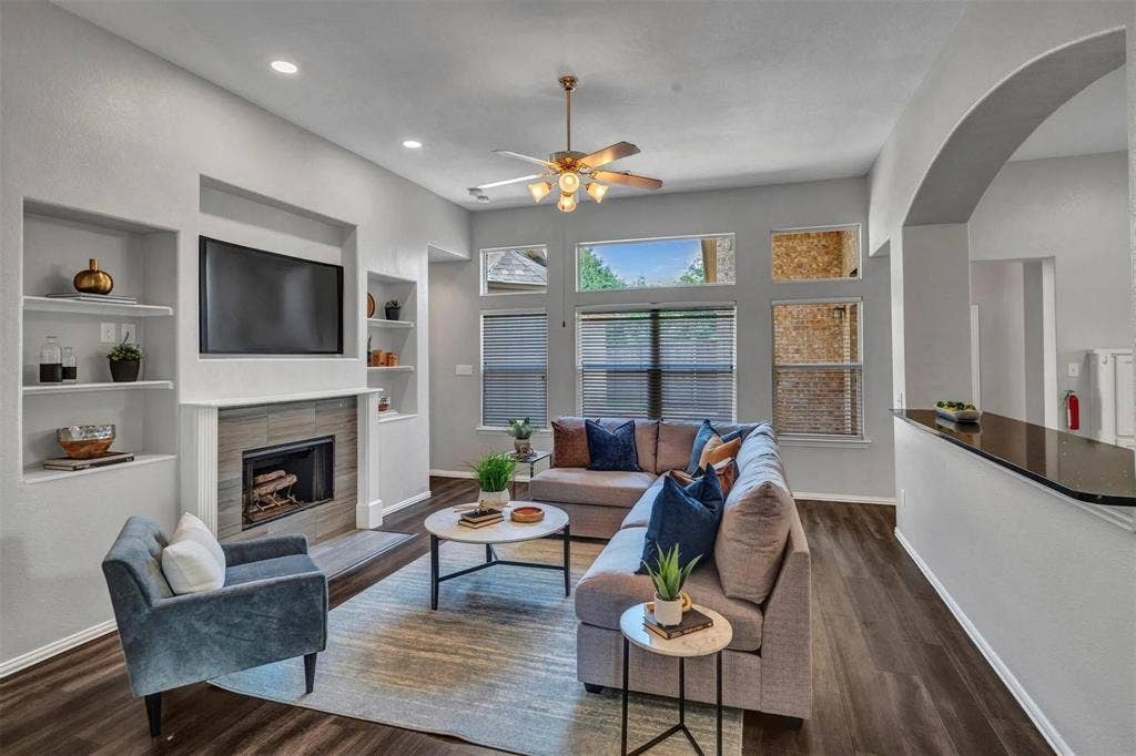 1601 Long Prairie Court, Allen, TX 75002 Sophisticated living room showcasing hardwood flooring, a linear gas fireplace with built-in cabinetry, and recessed ceiling lighting