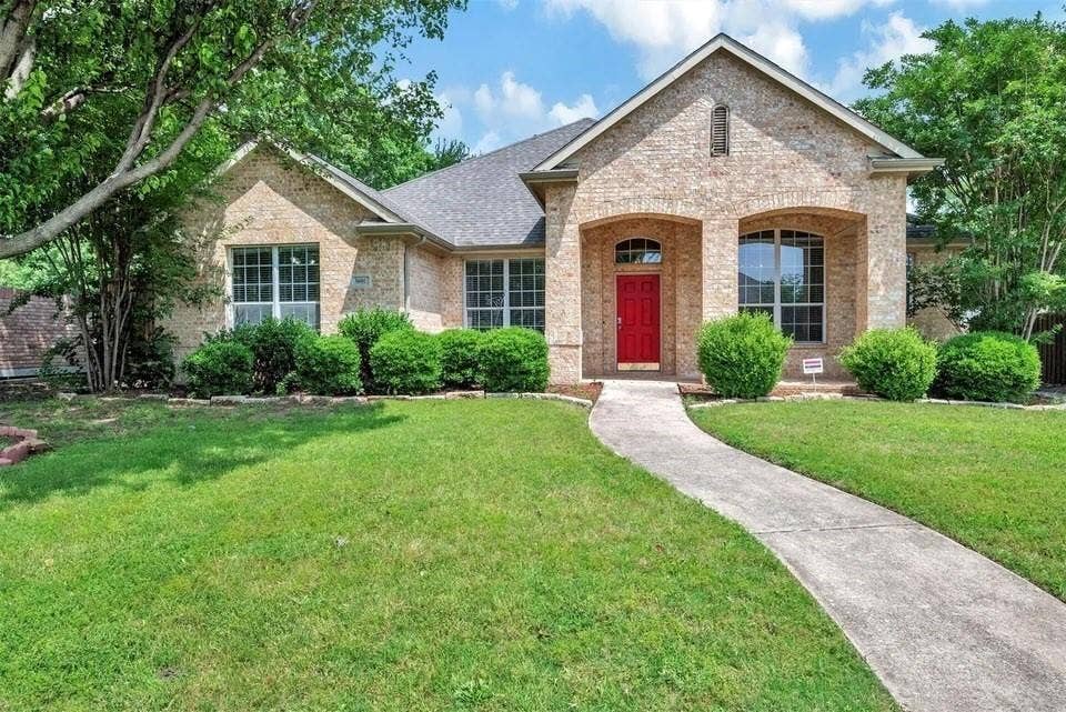 1601 Long Prairie Court, Allen, TX 75002 Charming brick residence featuring a welcoming red entry door, arched architectural detailing, and multi-pane windows with contrasting trim