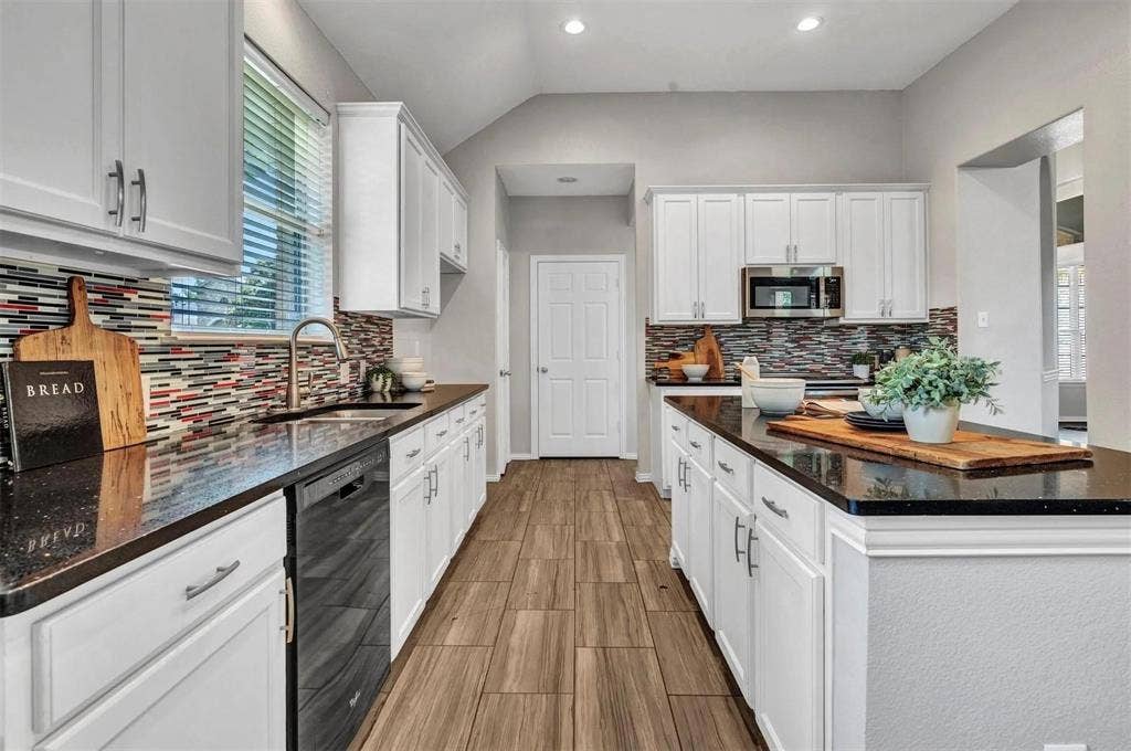1601 Long Prairie Court, Allen, TX 75002 Kitchen featuring white cabinetry, dark countertops, a multi-colored tile backsplash, stainless steel appliances, and wood-finish flooring