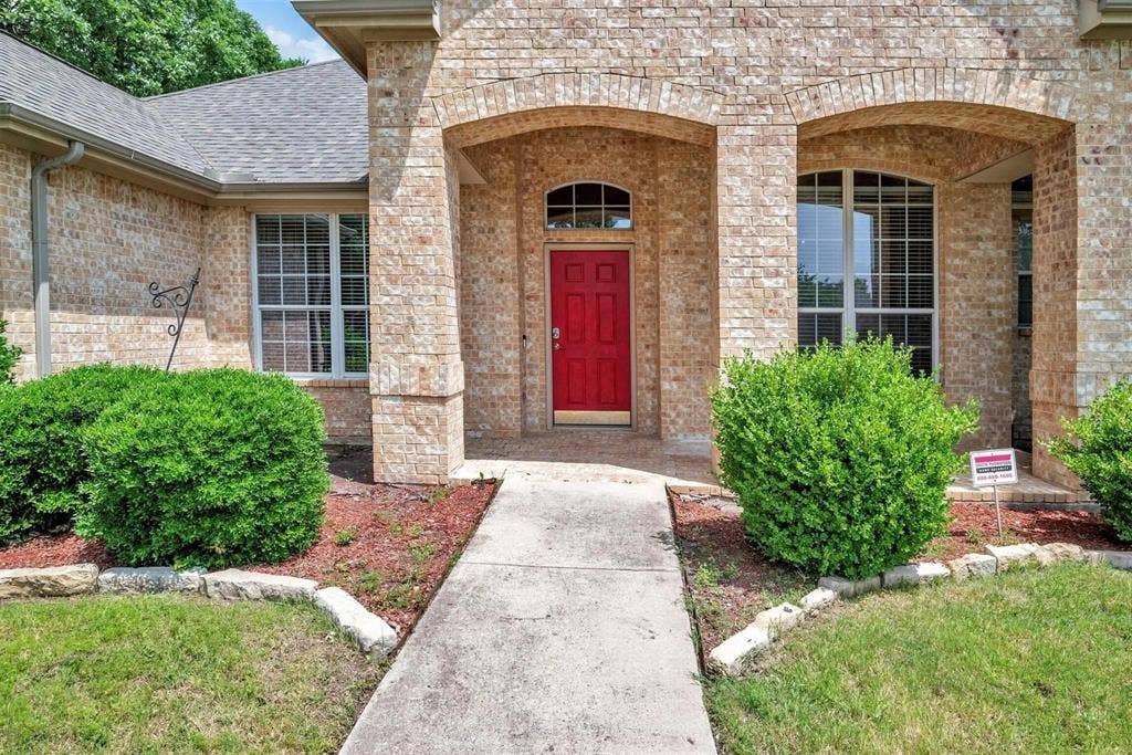 1601 Long Prairie Court, Allen, TX 75002 Brick exterior featuring an arched entry, a red front door, and a concrete pathway