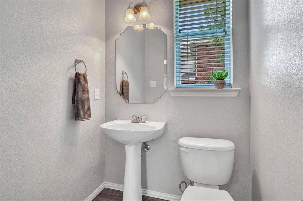 1601 Long Prairie Court, Allen, TX 75002 Pedestal sink, wall-mounted light fixture, decorative mirror, window with blinds, and wood-finish flooring