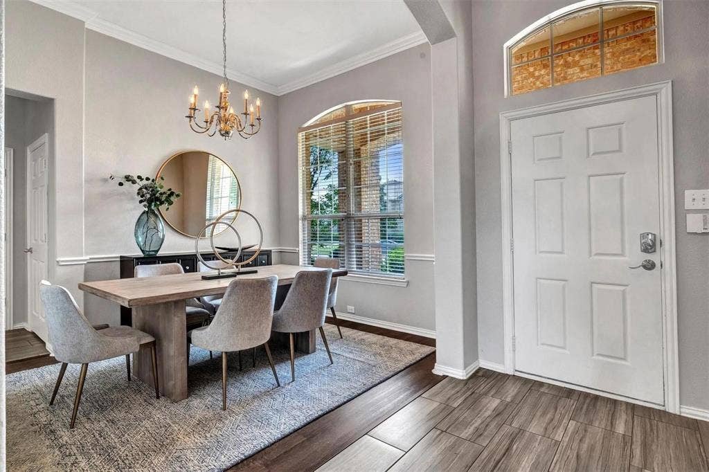 1601 Long Prairie Court, Allen, TX 75002 Arched window with blinds, decorative wall trim, wood-finish flooring, white paneled door, and an overhead chandelier
