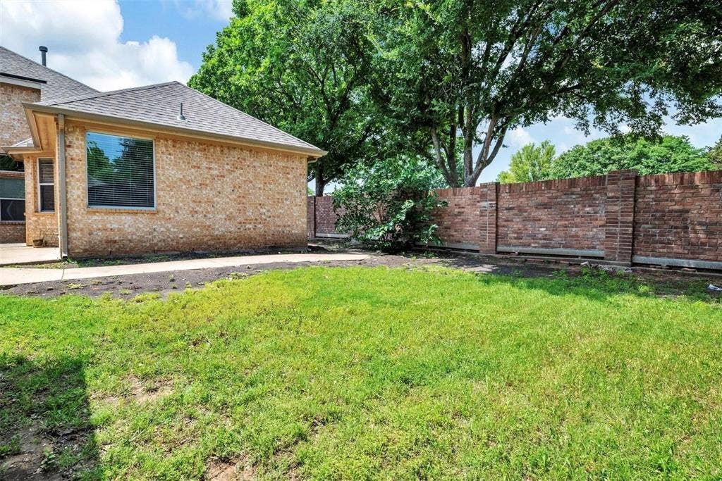 1601 Long Prairie Court, Allen, TX 75002 Brick exterior with a gabled roof, a large window, a concrete patio, and a brick privacy wall
