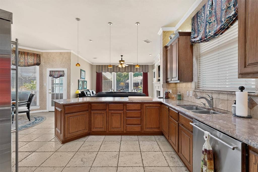 3820 Nash Lane, Plano, TX 75025 Kitchen featuring a central island, wood-finish cabinetry, stone countertops, and tile flooring