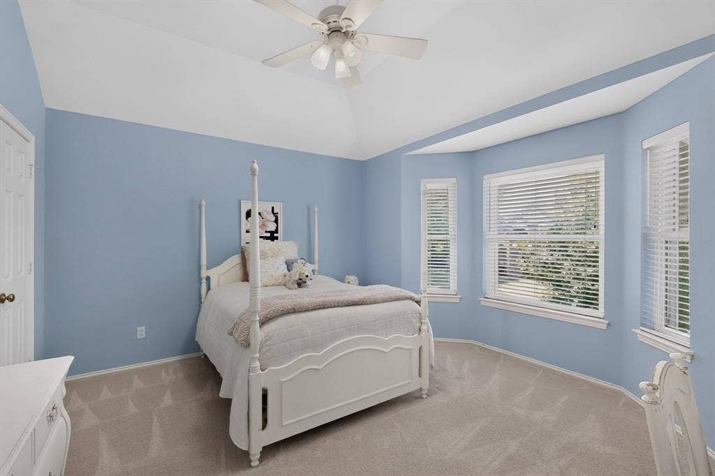 3820 Nash Lane, Plano, TX 75025 Vaulted ceiling with ceiling fan, bay window with multiple windows, light blue wall paint, paneled interior door, and carpet flooring