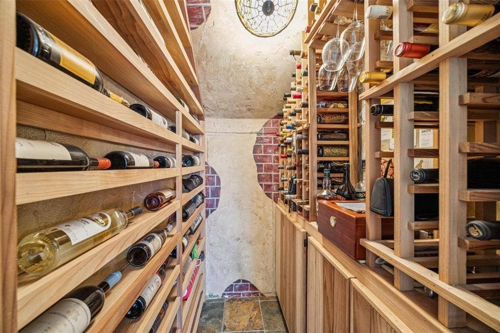 3820 Nash Lane, Plano, TX 75025 Dedicated wine cellar with extensive wood bottle shelving, integrated storage cabinets, and a unique brick and stucco wall treatment