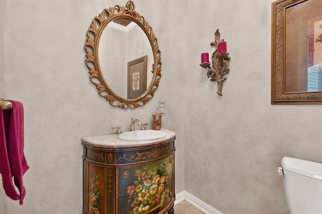 3820 Nash Lane, Plano, TX 75025 Ornate framed mirror over a console vanity with a built-in basin and brass-tone faucet